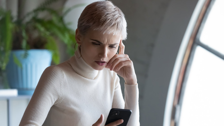 Woman frowning at smartphone