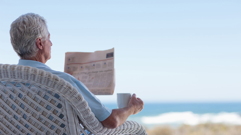 man reading newspaper outside