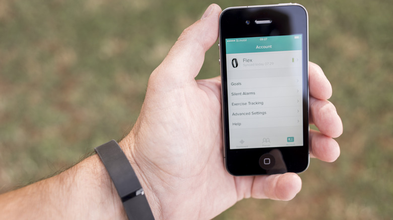 Fitbit fitness tracker on an arm and Fitbit app on iPhone