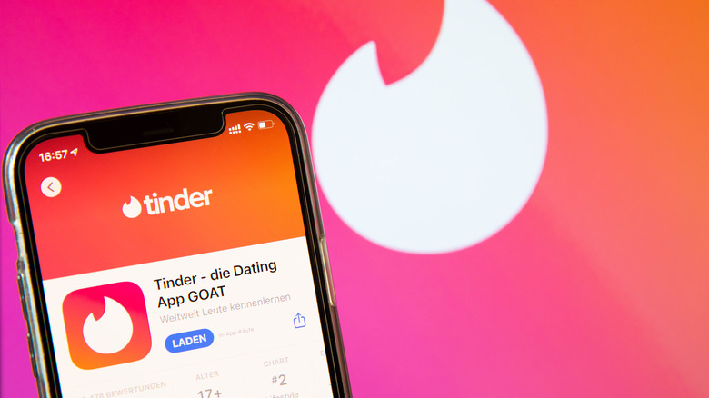 Tinder app on an iPhone and logo in background