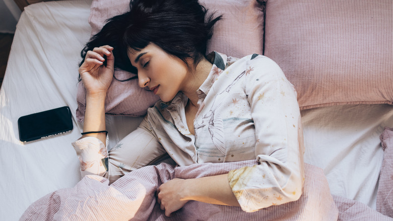 person sleeping in bed with smartphone