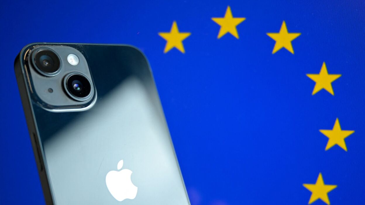 An iPhone being held in front of a backdrop of the EU flag