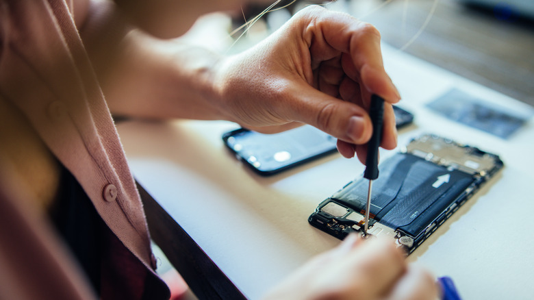 Woman using screw to fix inside of phone