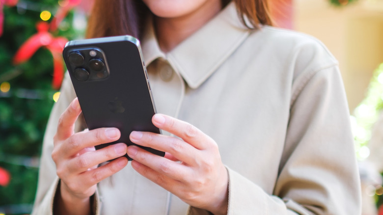 A faceless woman is looking at something on her iPhone