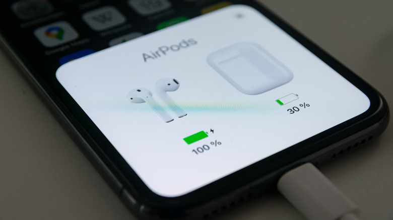 Close up of an iPhone connected to charger showing AirPods battery