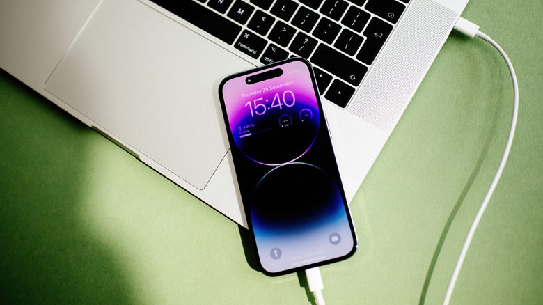 An iPhone connected to a MacBook with a Lightning to USB cable.
