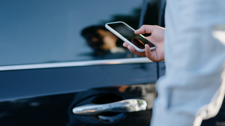 Person holding a phone near a car