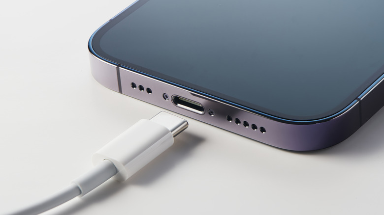 A USB-C cable next to the charging port of an iPhone