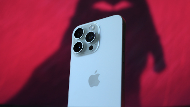 A white iPhone 15 Pro Max against a red background