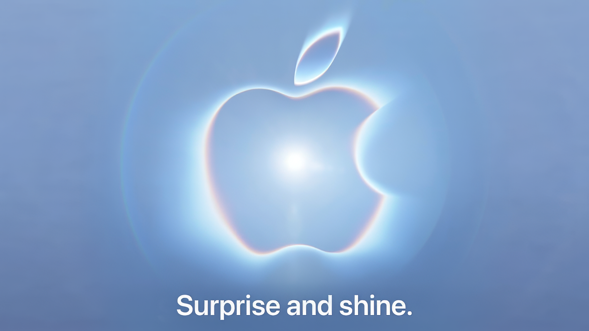 Apple graphic showing its logo with a bright light at the center on a blue-gray background. Text: reads surprise and shine